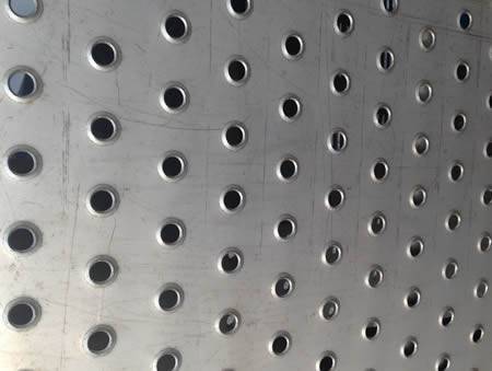 A piece of stainless steel checker plate semi raised round projections.