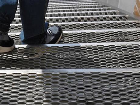 A man is stepping on the aluminum expanded metal stair treads.