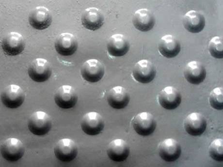 A piece of iron checker plate with raised round projections.